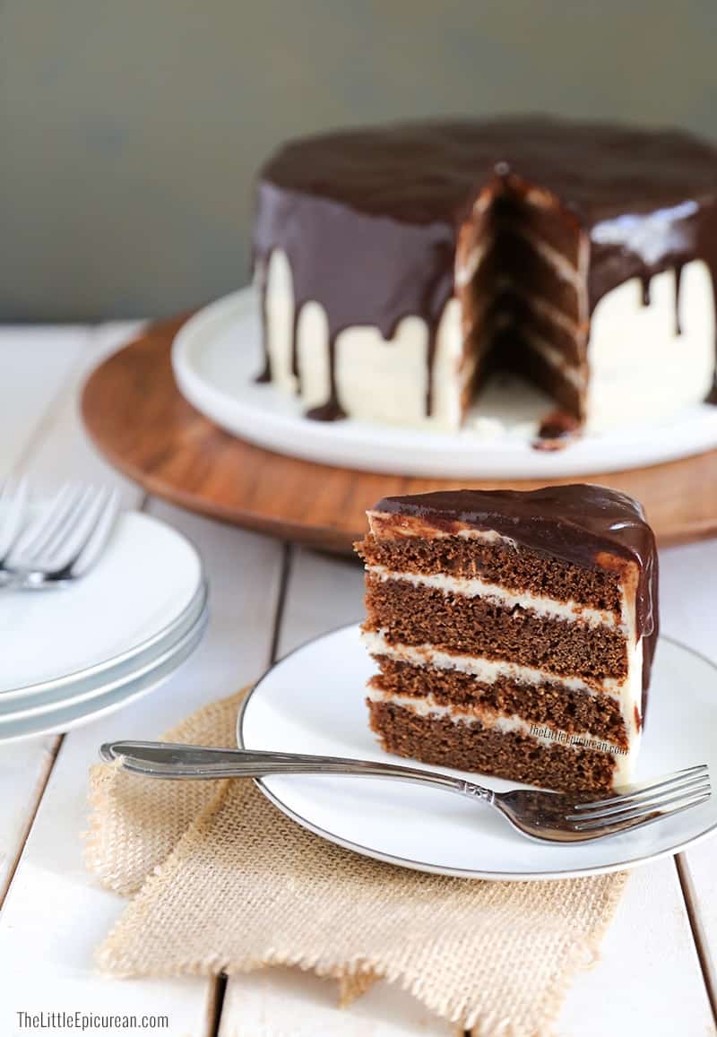 slice of chocolate cake frosted with whiskey cream cheese frosting and topped with rich chocolate glaze.