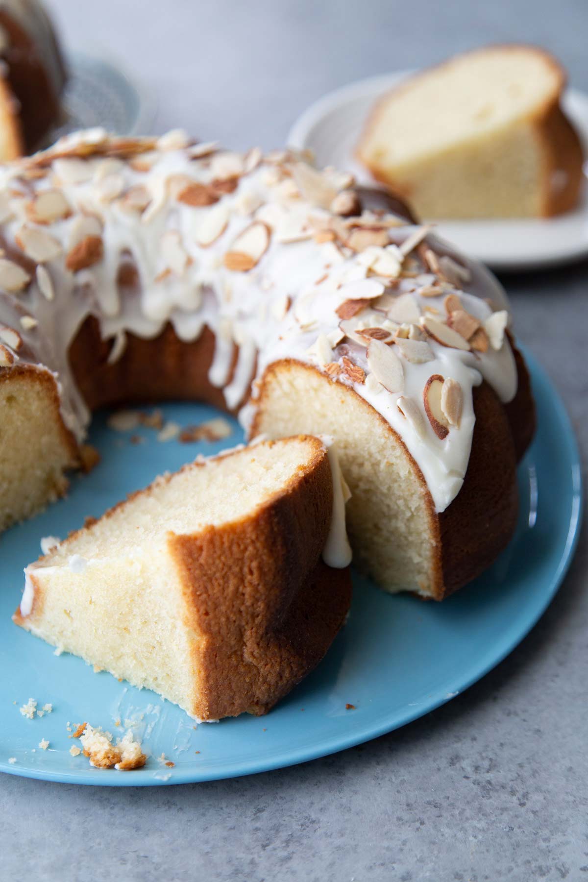 slice of glazed almond pound cake on blue serving plate.