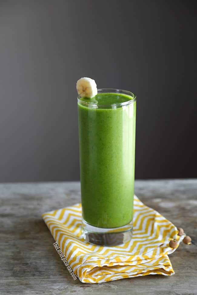 glass of green smoothie garnished with banana slice. 