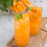 two glasses of cantaloupe agua fresca garnished with fresh mint.
