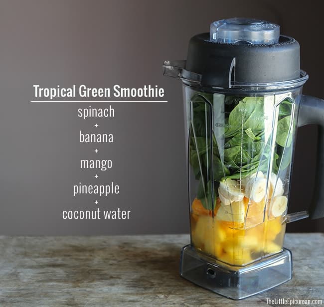 spinach leaves, sliced banana, mango chunks, pineapple chunks, and coconut water inside a blender.