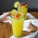 ginger peach cooler cocktail garnished with fresh peach slice and lime wheel.
