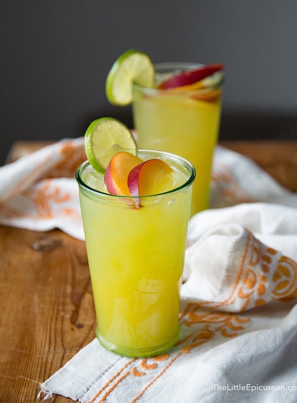 ginger peach cooler cocktail garnished with fresh peach slice and lime wheel.