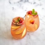 two glasses of stone fruit sangria on marble table.