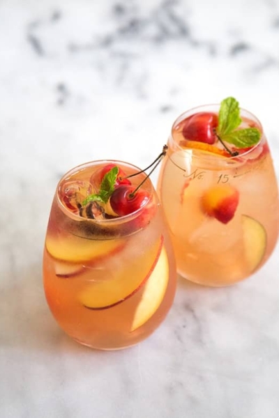 two glasses of stone fruit sangria on marble table.