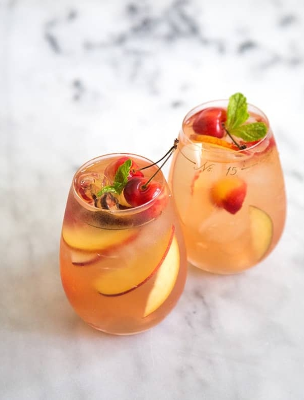 two glasses of stone fruit sangria on marble table.