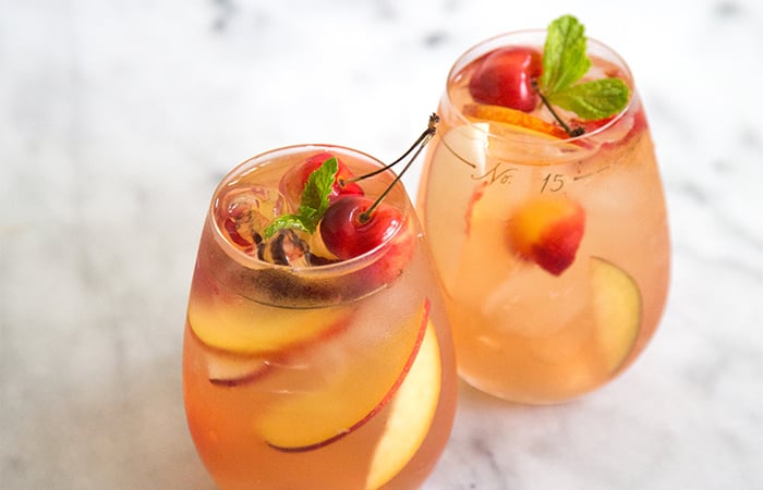 two glasses of stone fruit sangria on marble table.