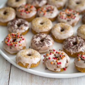 Mini Baked Pumpkin Donuts with cinnamon glaze on white serving plate.