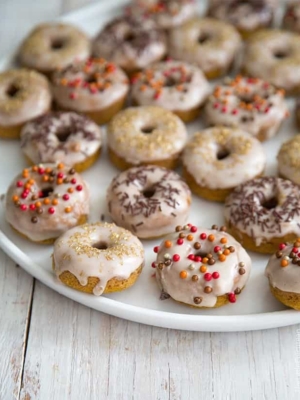 Mini Baked Pumpkin Donuts with cinnamon glaze on white serving plate.