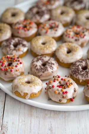 Mini Baked Pumpkin Donuts with cinnamon glaze on white serving plate.