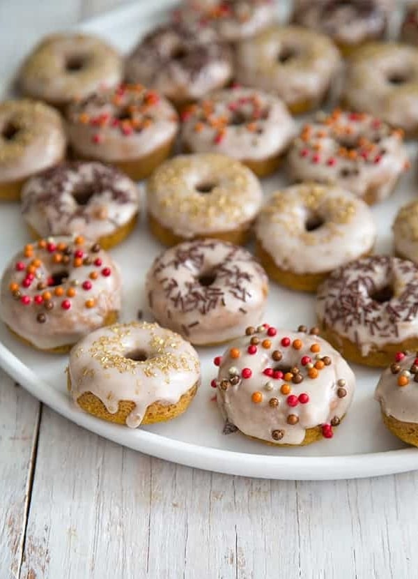 Mini Baked Pumpkin Donuts with cinnamon glaze on white serving plate.