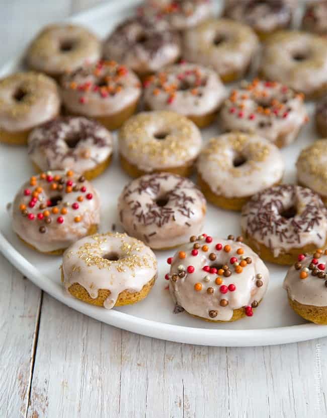 Mini Baked Pumpkin Donuts with cinnamon glaze on white serving plate.