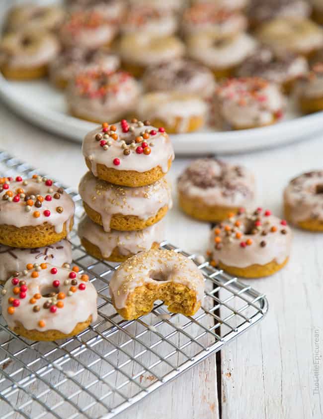 mini glazed pumpkin donuts stacked on wire rack.