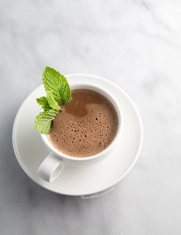 mint hot chocolate in white cup garnished with fresh mint leaves.