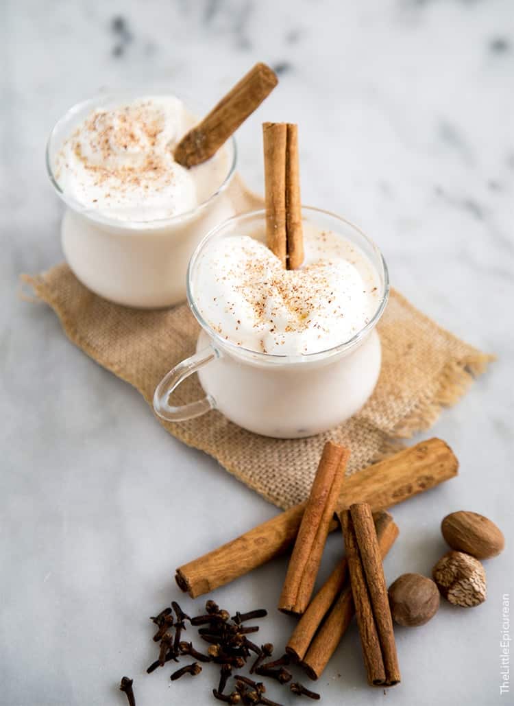 spiced milk with whiskey topped with whipped cream garnished with cinnamon stick.
