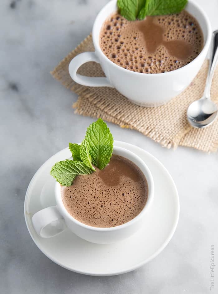 two cups of mint hot chocolate garnished with fresh mint. 