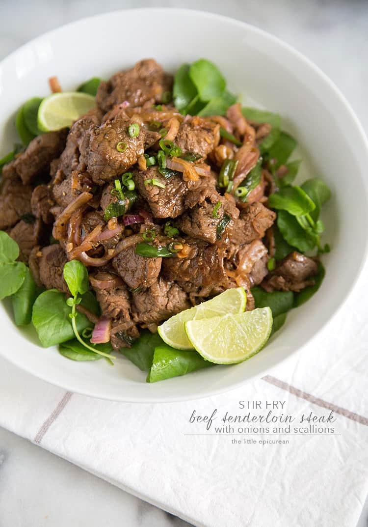 Stir Fry Beef with onions and scallions in white serving bowl.