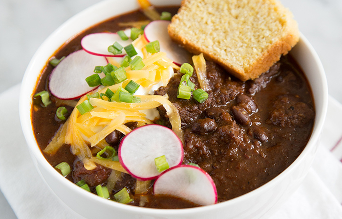Chipotle Steak Chili topped with sliced radish, shredded cheese, and green onions