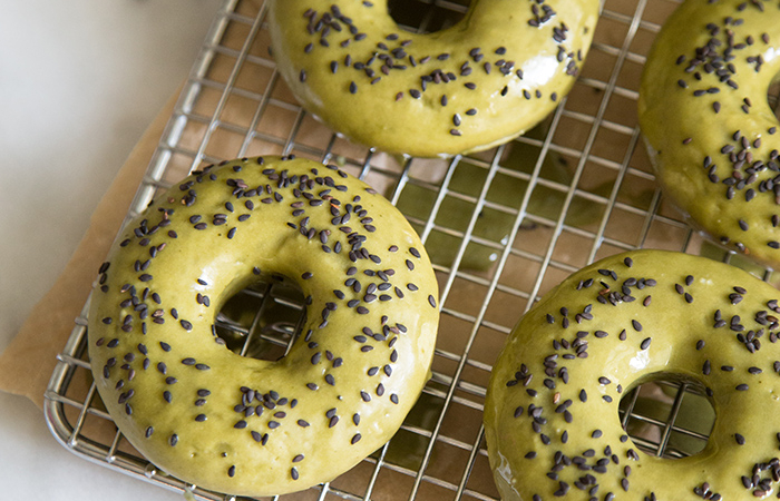 baked matcha doughnuts topped with black sesame seeds on wire cooling rack