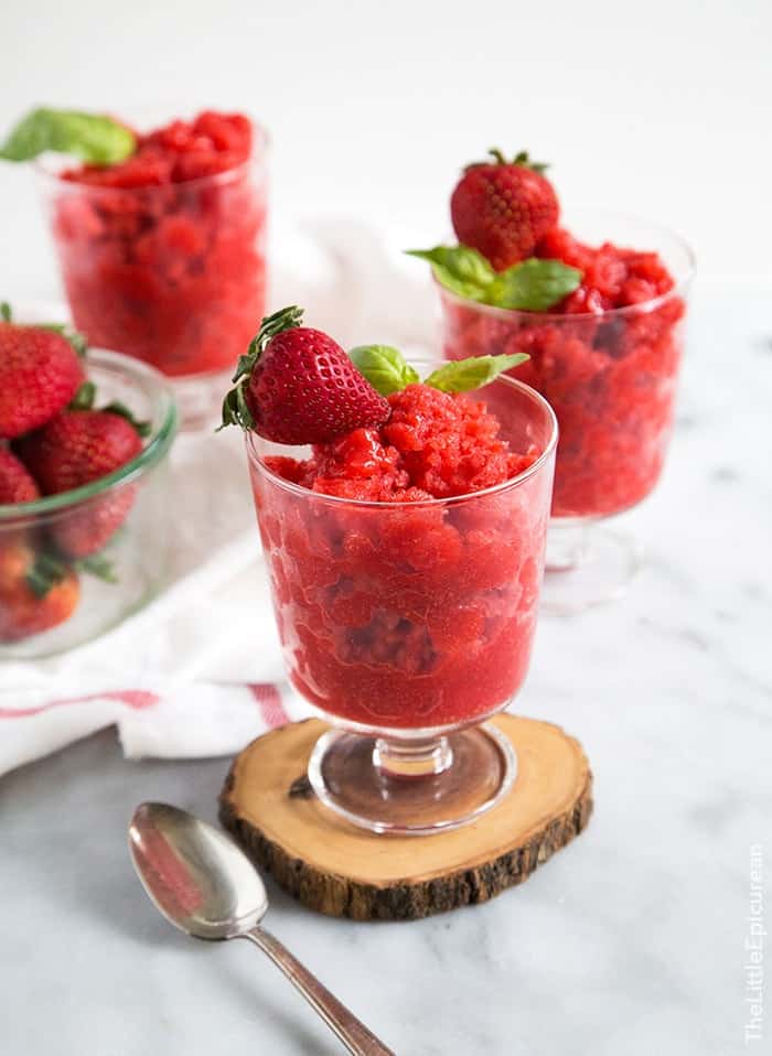 strawberry basil granita in serving glasses garnished with fresh strawberry and fresh basil sprig. 