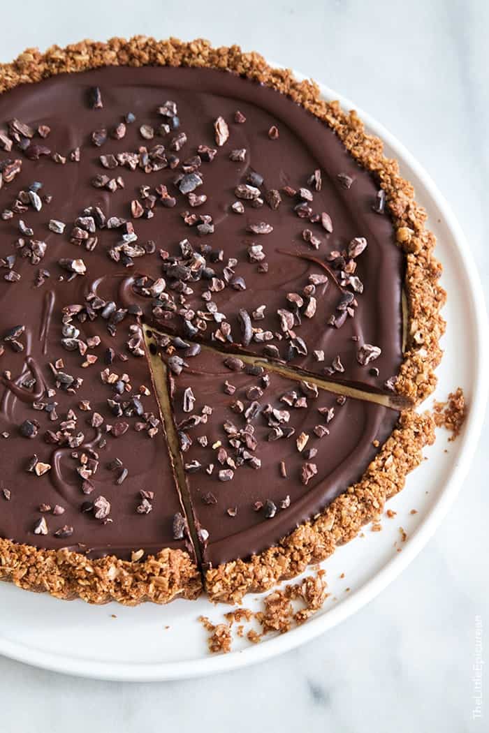 chocolate peanut butter oat tart with slice cut out on round white plate. 