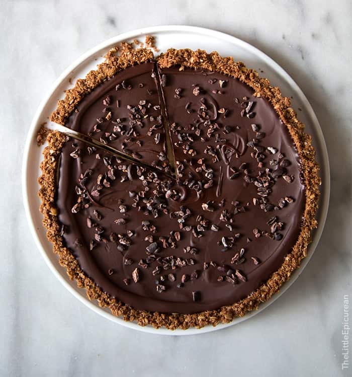 overhead of chocolate peanut butter oat tart topped with crunchy cacao nibs. 