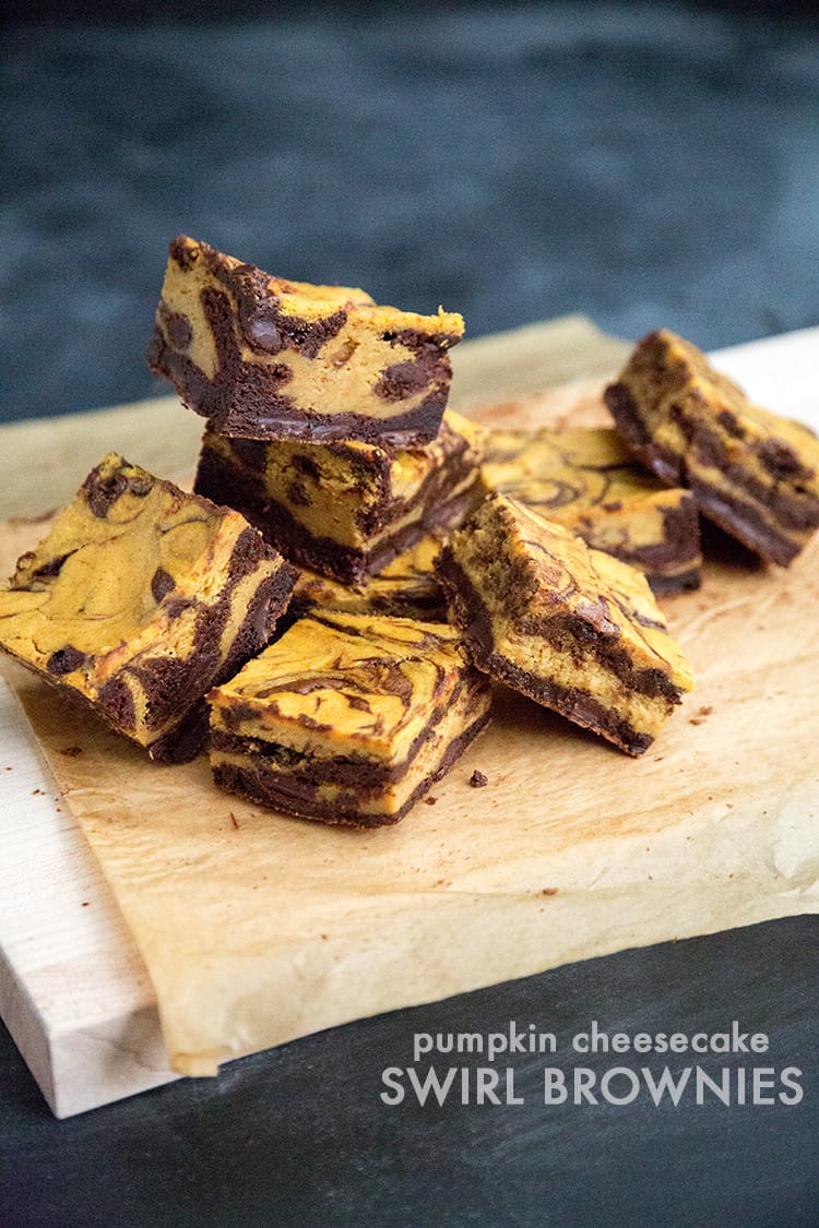 portioned slices of pumpkin cheesecake swirl brownies on cutting board.