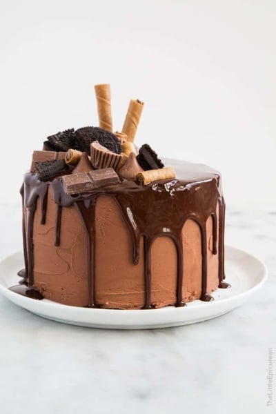 super decadent chocolate layer cake topped with chocolate ganache, chocolate candy bars, and chocolate cookies.