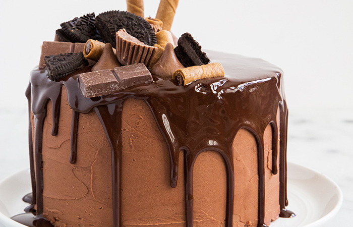 super decadent chocolate layer cake topped with chocolate ganache, chocolate candy bars, and chocolate cookies.