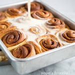 glaze being poured on fresh baked cinnamon rolls.