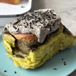 matcha rolls with black sesame filling and black sesame cream cheese frosting on blue plate.