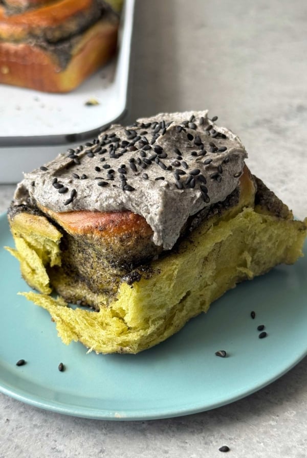 matcha rolls with black sesame filling and black sesame cream cheese frosting on blue plate.
