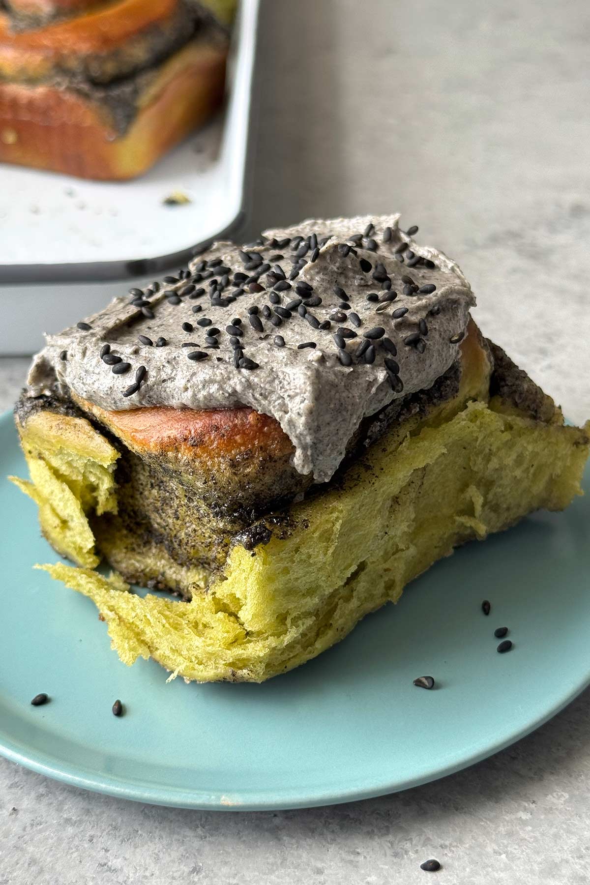 matcha rolls with black sesame filling and black sesame cream cheese frosting on blue plate.