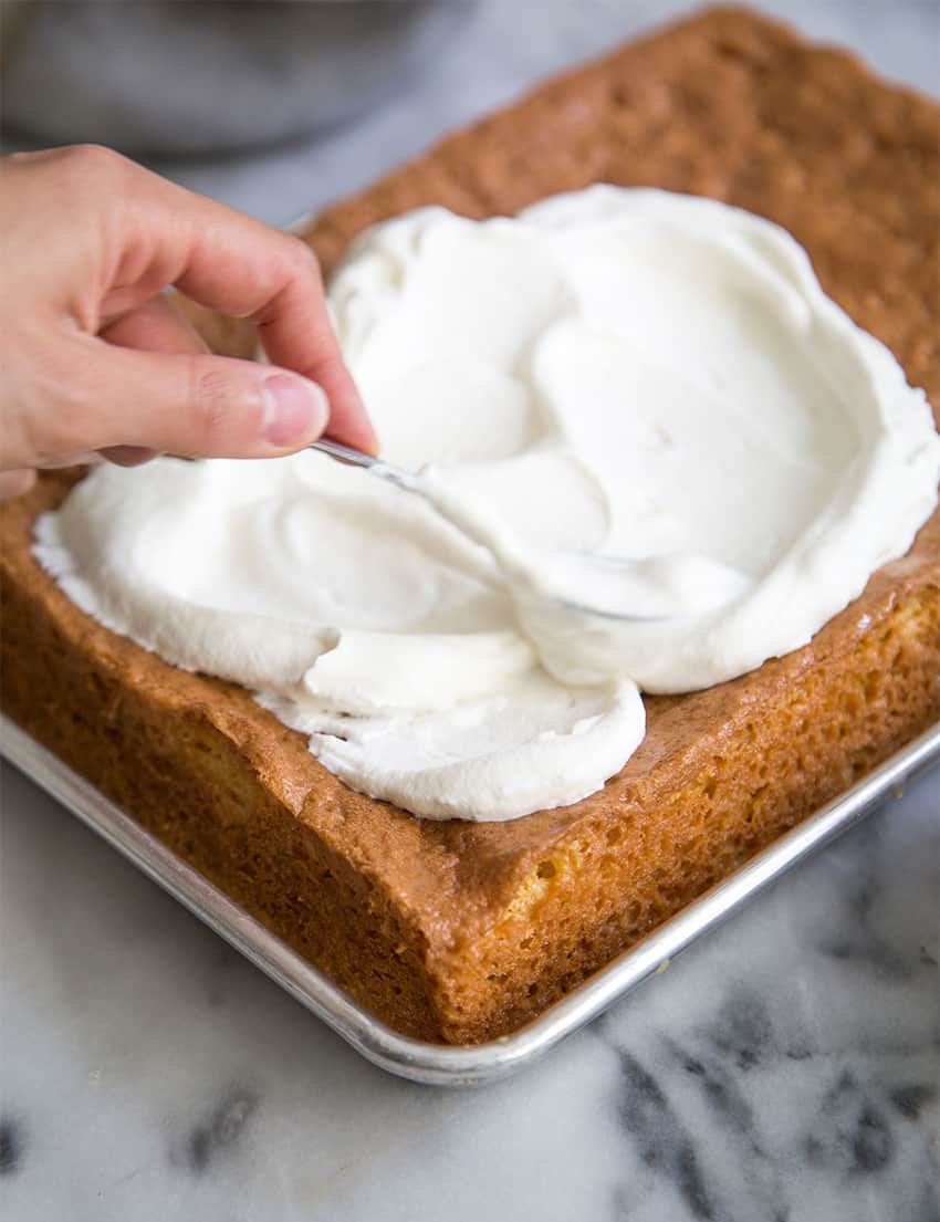 whipped cream spread on vanilla sponge cake.