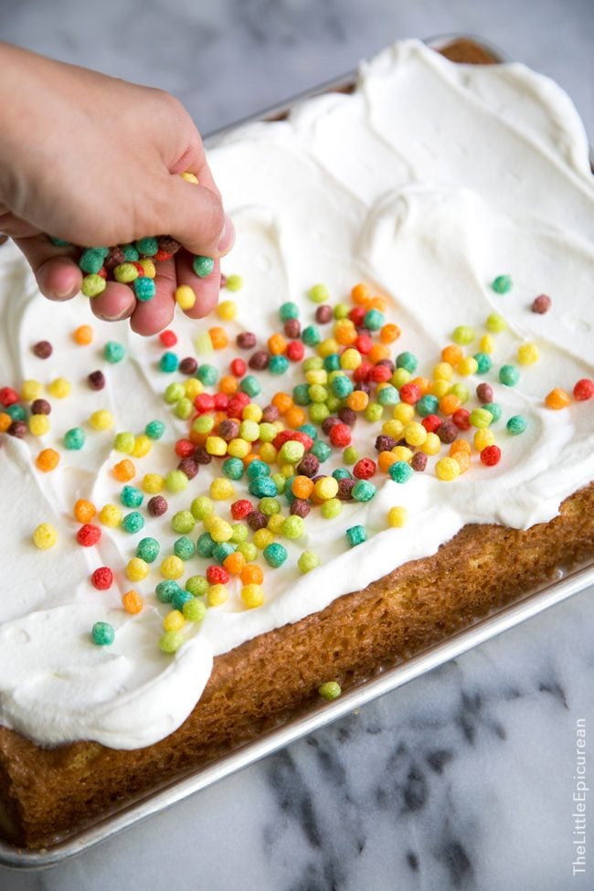 colorful cereal sprinkled on whipped cream topped tres leches cake.