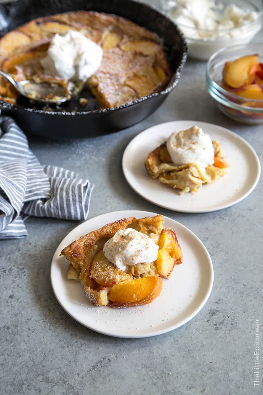 serving on peach clafoutis topped with whipped cream.
