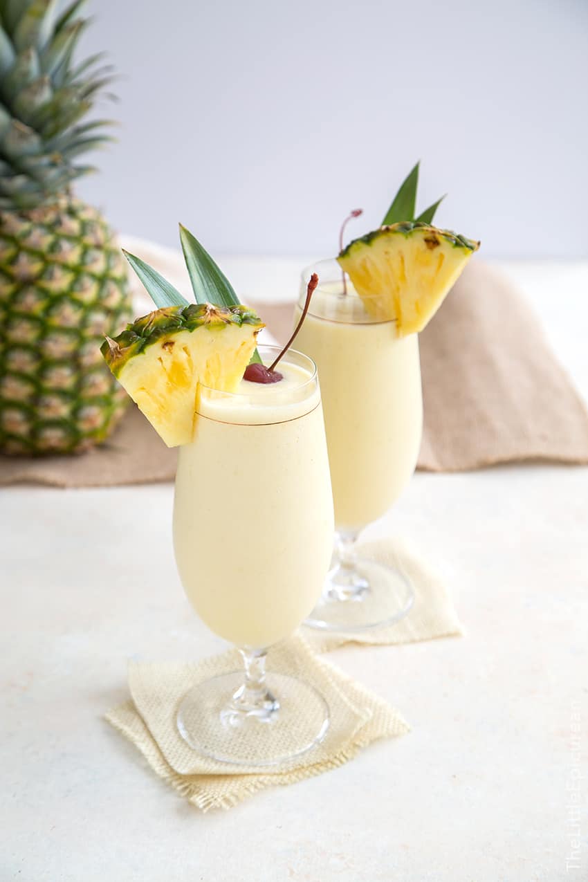 two glasses of frozen Pina Colada in stemmed glassware. 