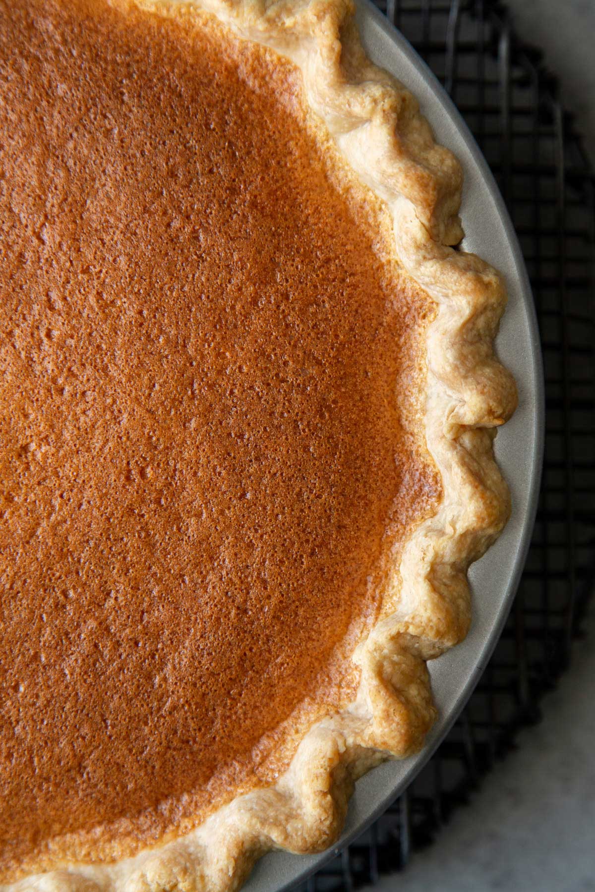 close up of Filipino egg custard pie in tin on cooling rack.