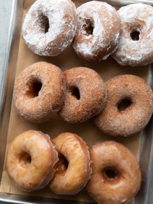 three versions of buttermilk donuts include powdered sugar, cinnamon sugar, and sweet glaze.