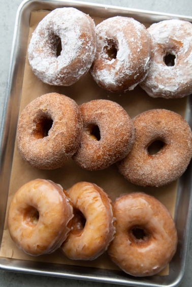 three versions of buttermilk donuts include powdered sugar, cinnamon sugar, and sweet glaze.