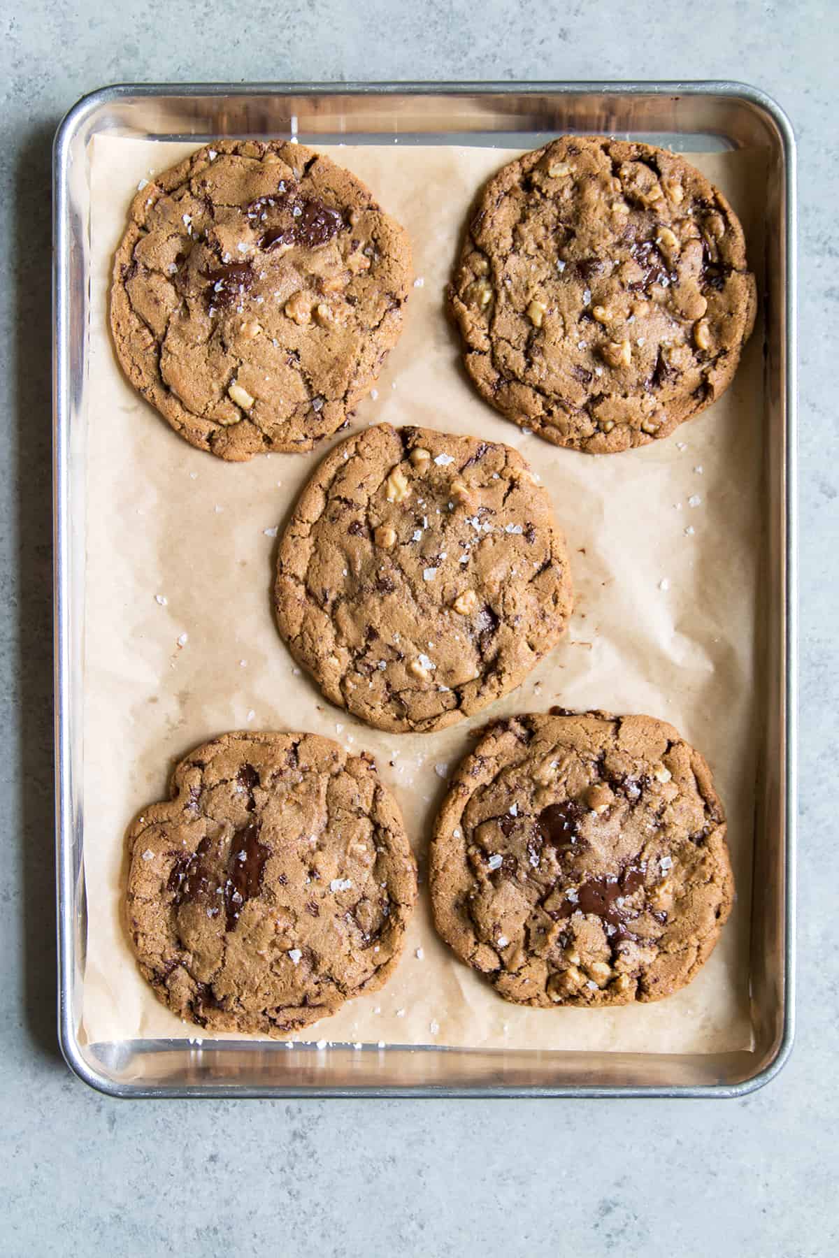 5 Giant Chocolate Chip Cookies on parchment lined sheet tray.