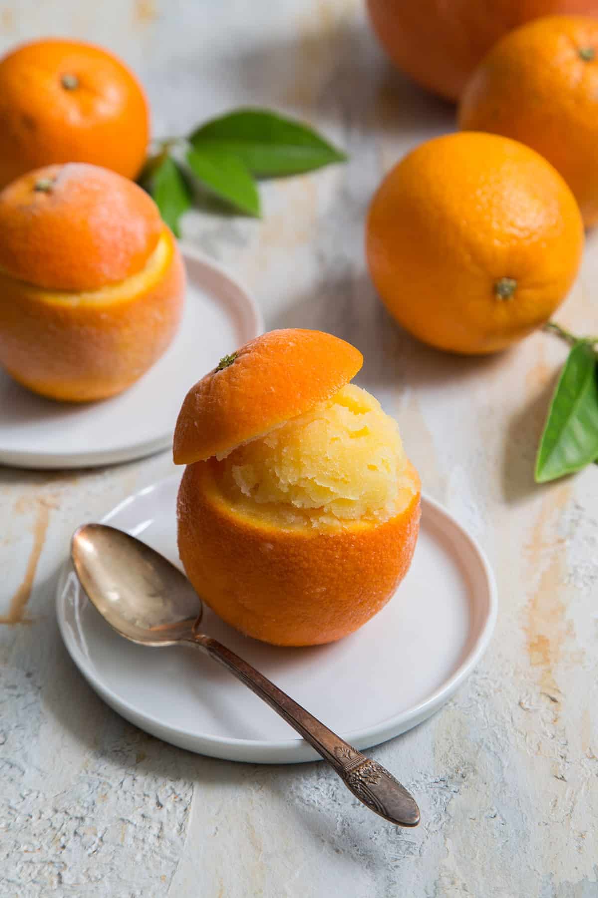 homemade orange sorbet served in orange shell cup on a white plate. 