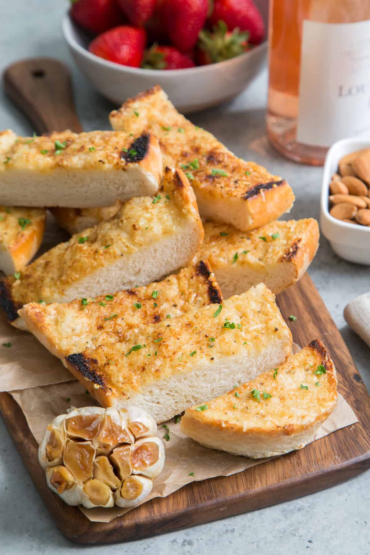 roasted garlic bread slices on wooden serving board. 