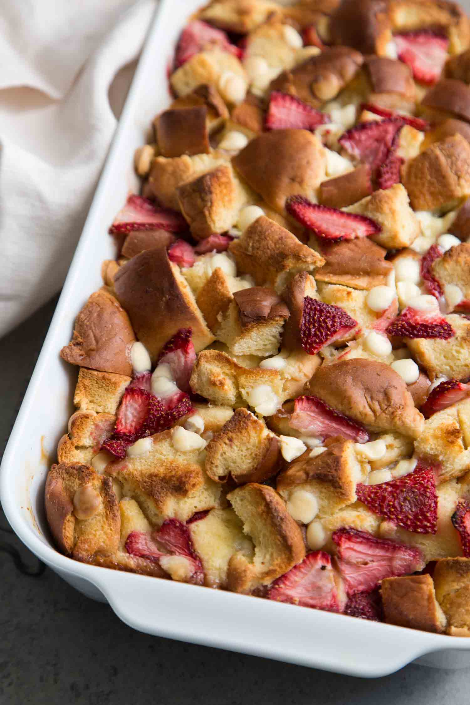 White Chocolate Strawberry Bread Pudding in white casserole dish. 