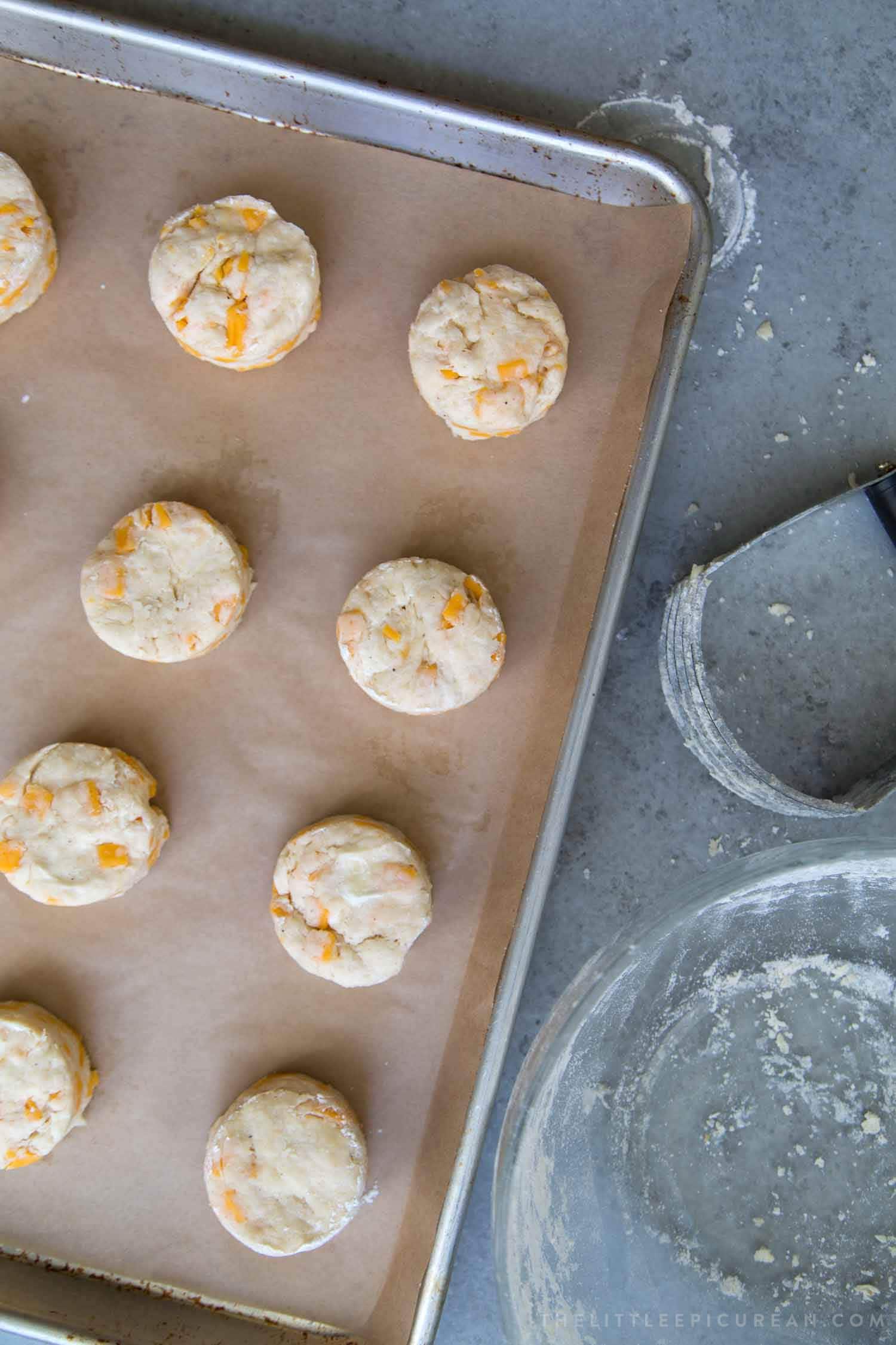 cheesy cheddar biscuits on parchment lined baking sheet.