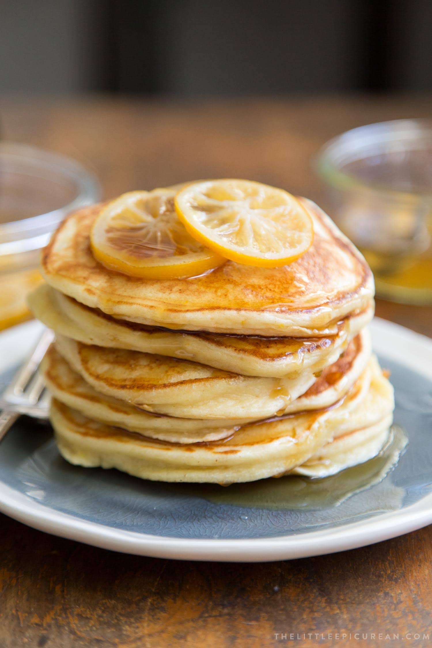 Meyer Lemon Ricotta Pancakes staked tall on blue plate and garnished with Meyer lemon candied slices. 