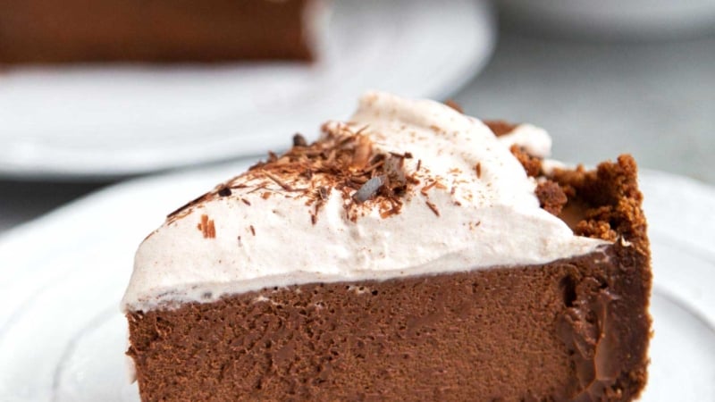 Slice of Chocolate Mousse Pie. Chocolate graham cracker crust filled with chocolate mousse and topped with whipped cream and chocolate shavings.