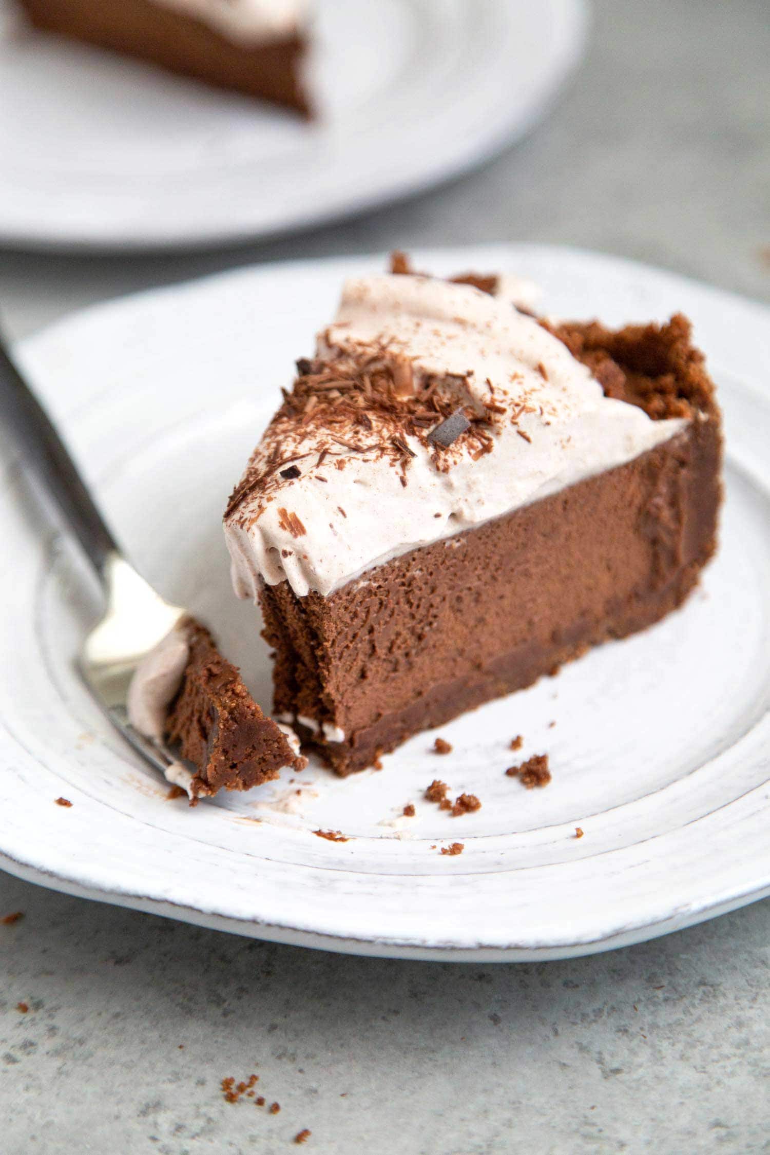 Slice of Chocolate Mousse Pie. Chocolate graham cracker crust filled with chocolate mousse and topped with whipped cream and chocolate shavings.