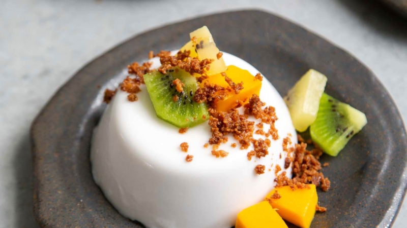 Coconut Panna Cotta served with latik and fresh fruits. Latik is from the Philippines. It is fried coconut milk curds.