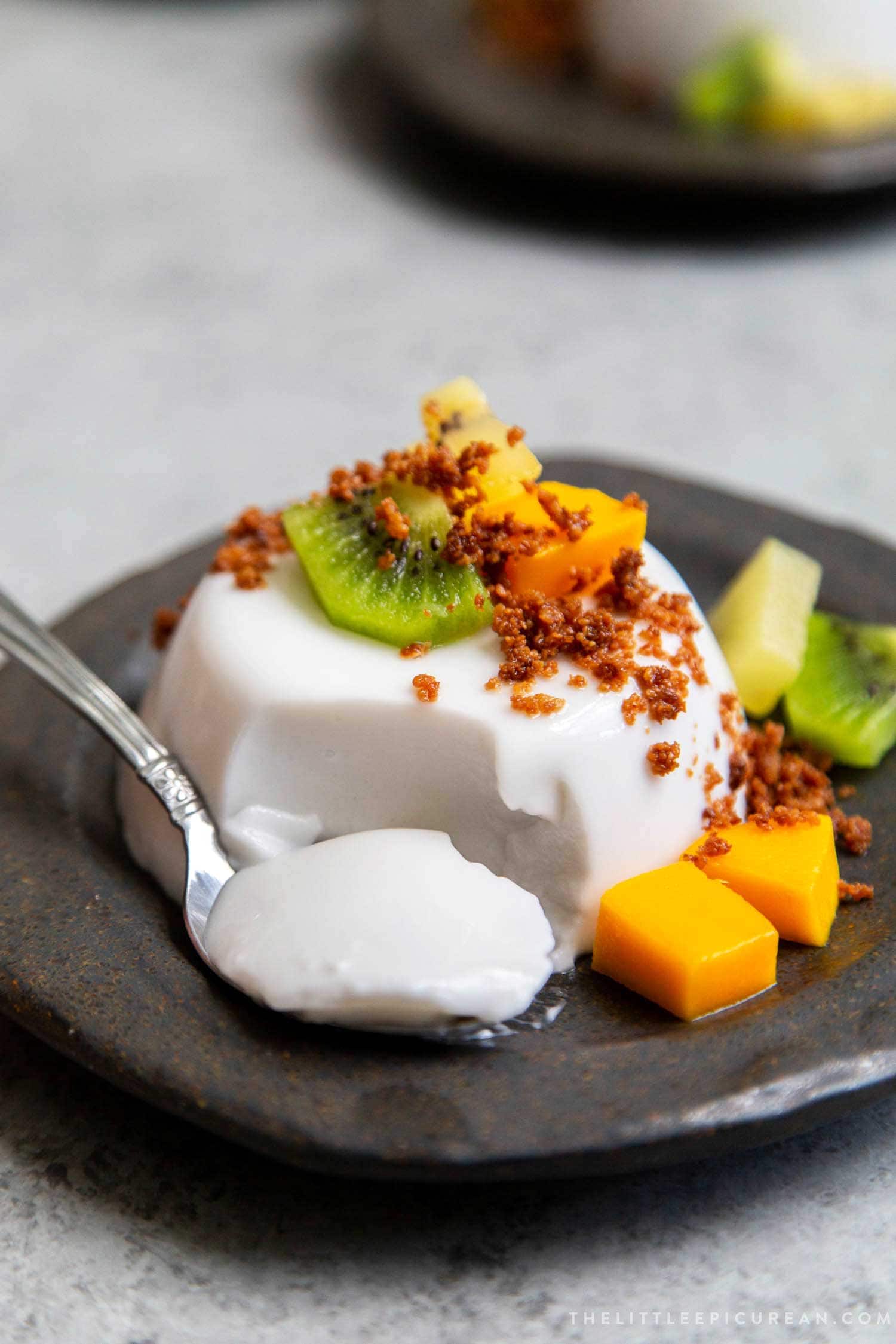 Coconut Panna Cotta served with latik and fresh fruits. Latik is from the Philippines. It is fried coconut milk curds.